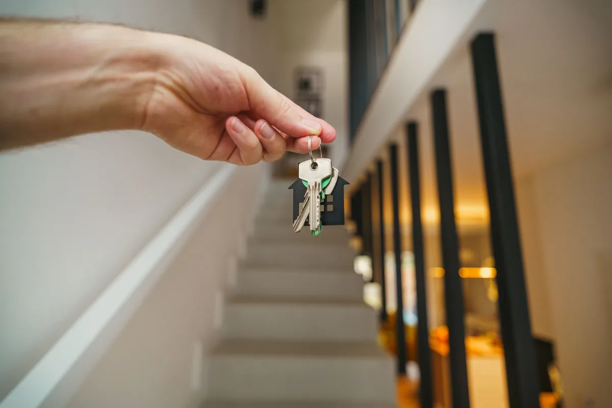 A hand carrying keys into the stairwell of a let property
