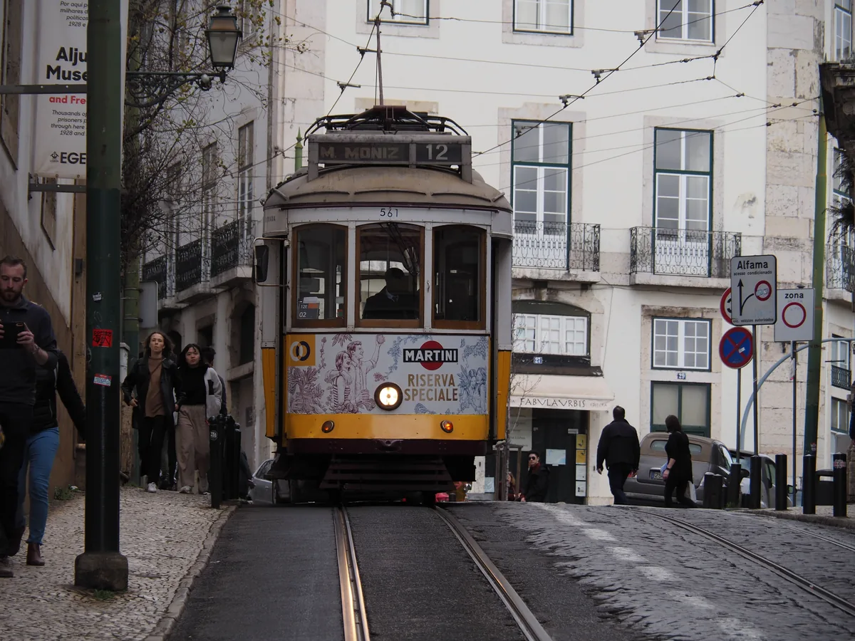 A yellow tram climbing a narrow street in Lisbon's Alfama