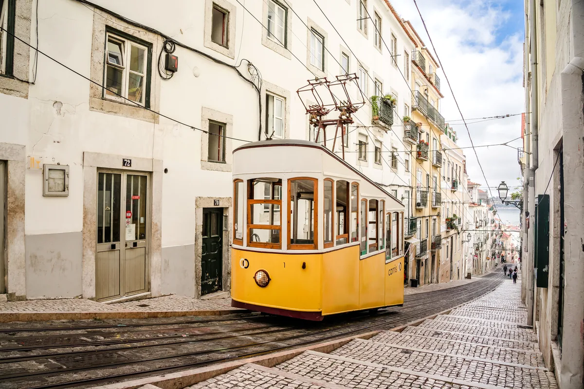 A yellow tram on a cobbled street in Lisbon
