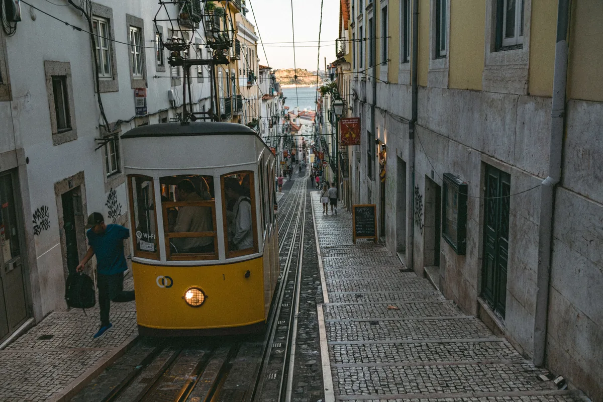 A vintage tram descending a steep cobbled street in Lisbon