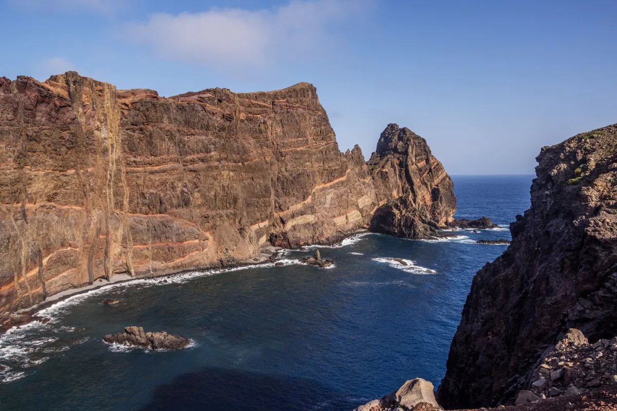 Ochre volcanic sea cliffs above deep blue water on Madeira