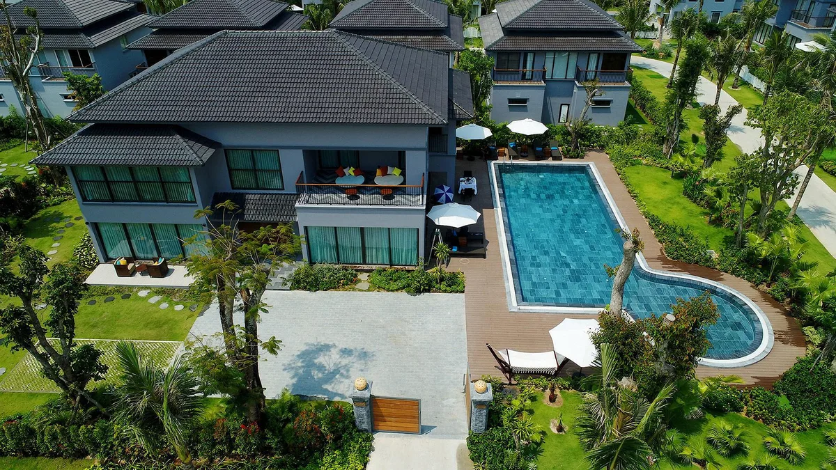 A modern villa with a pool and lawn seen from above