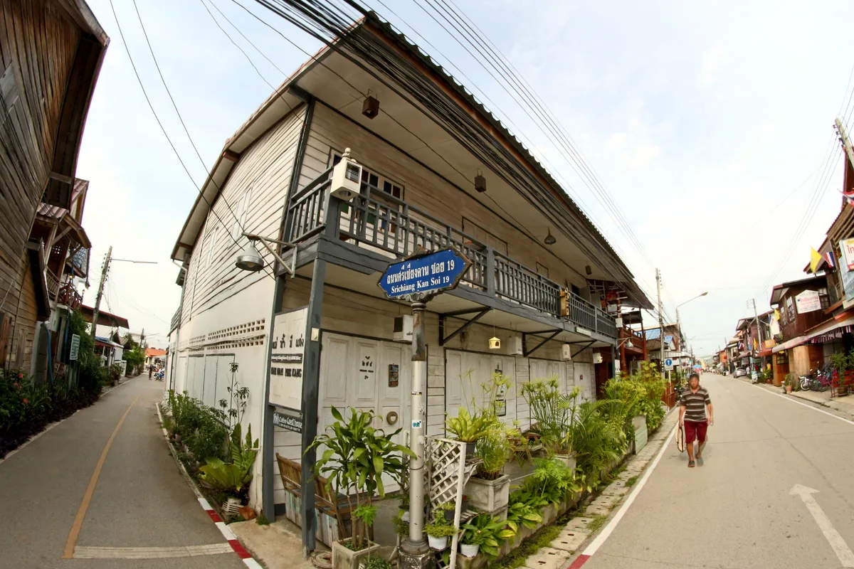 A shophouse street of weathered timber and shuttered fronts