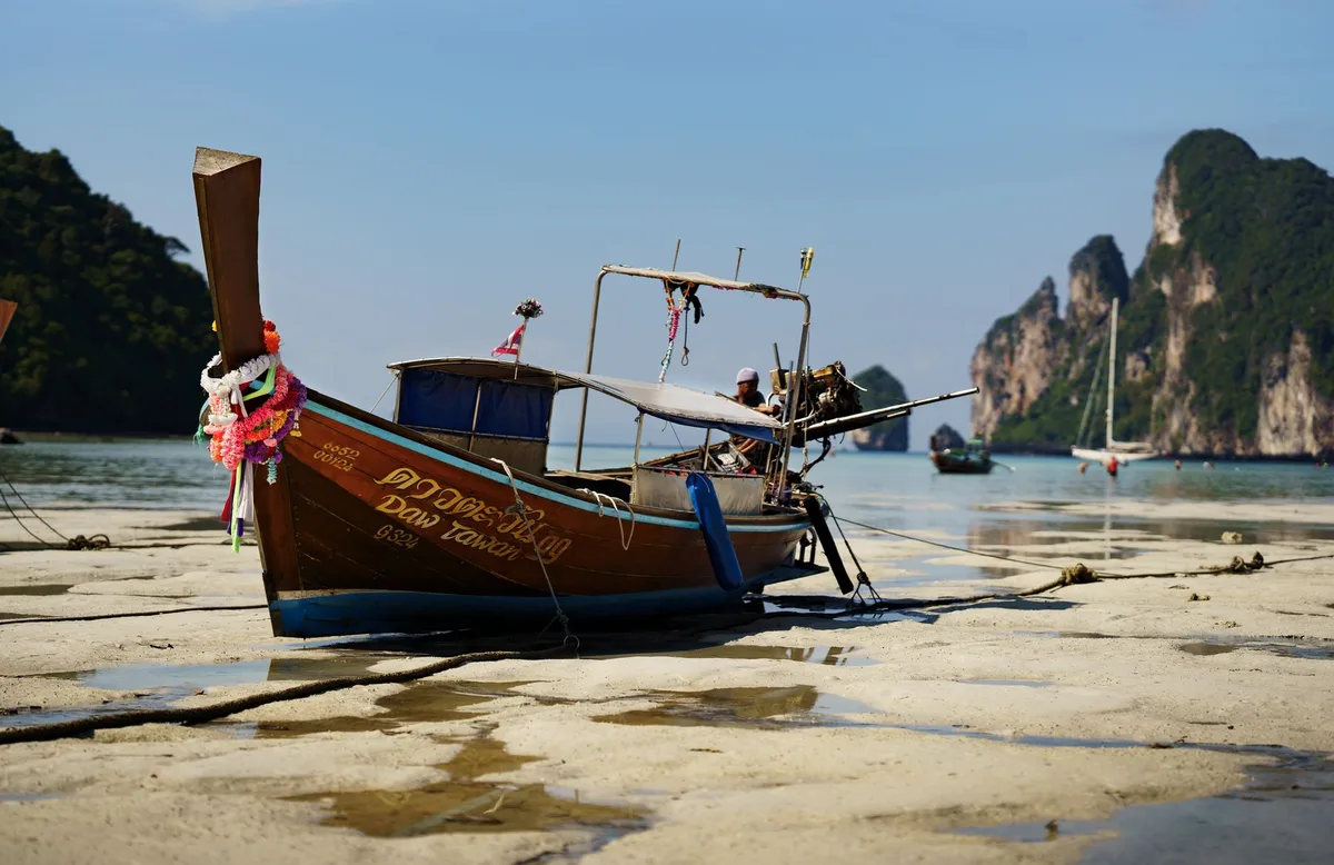 Thailand short-term rental management, longtail boat beached at low tide