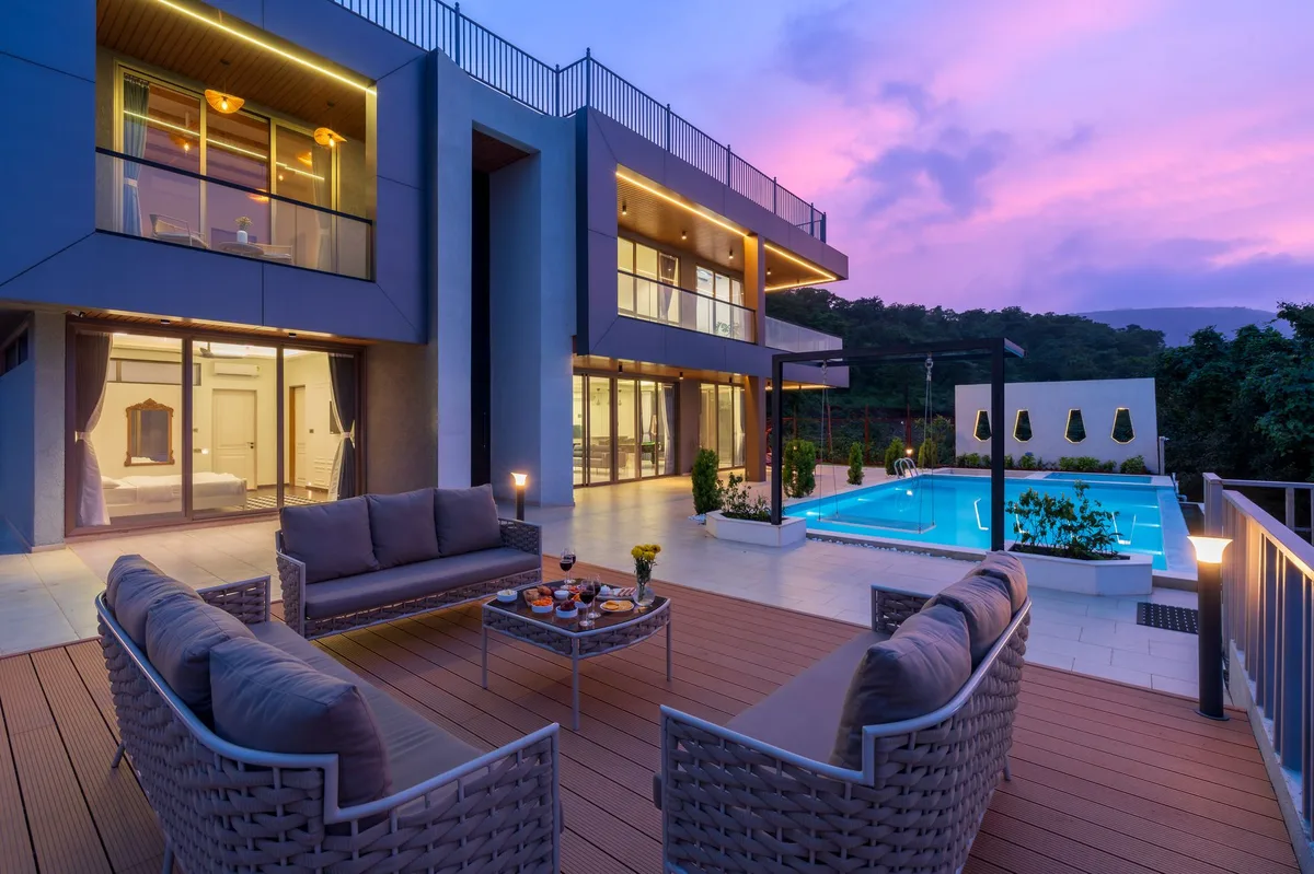 Villa management fees, modern two-storey villa with a pool terrace at dusk