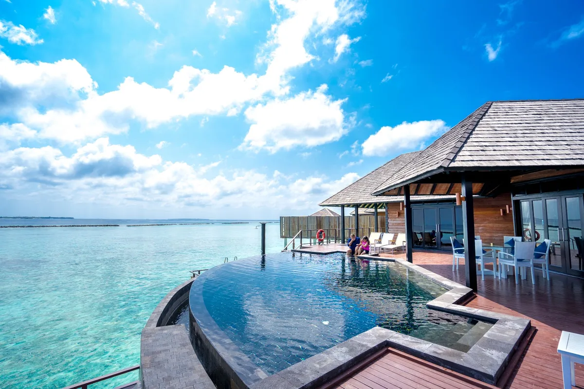An infinity pool and timber pavilion above shallow clear water
