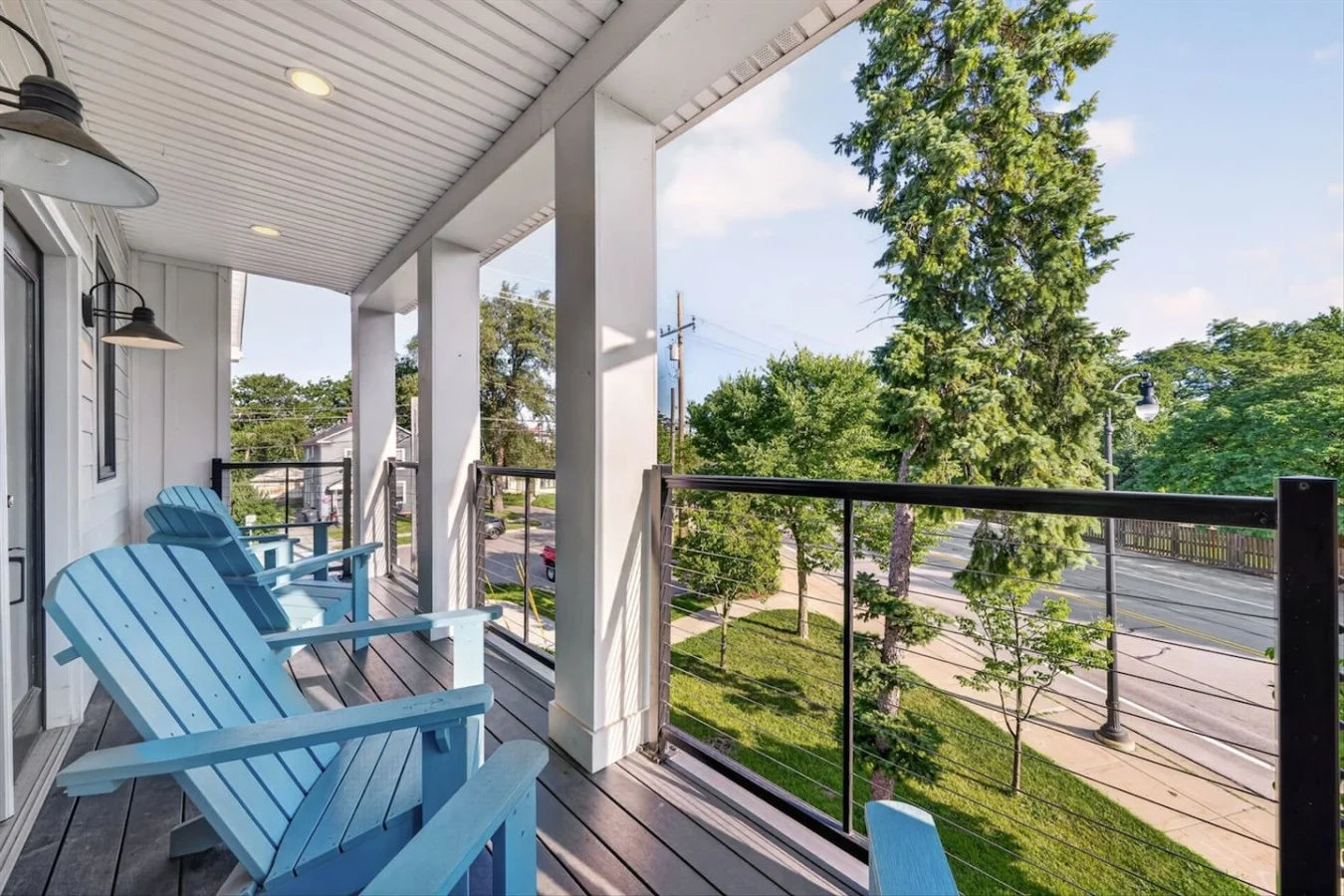 Covered porch with blue Adirondack chairs among trees in Ann Arbor