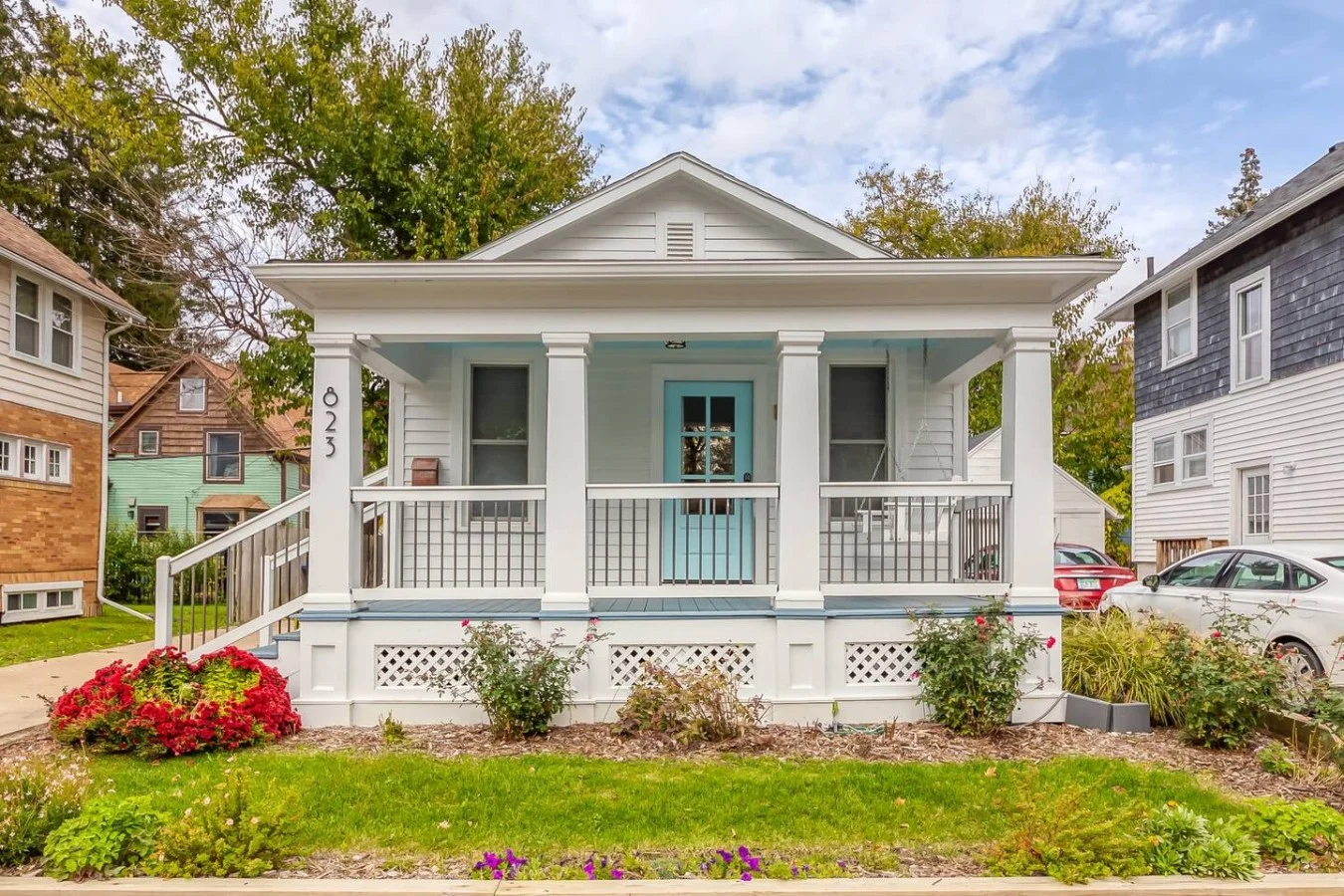 White house with a front porch and red flowers in Ann Arbor