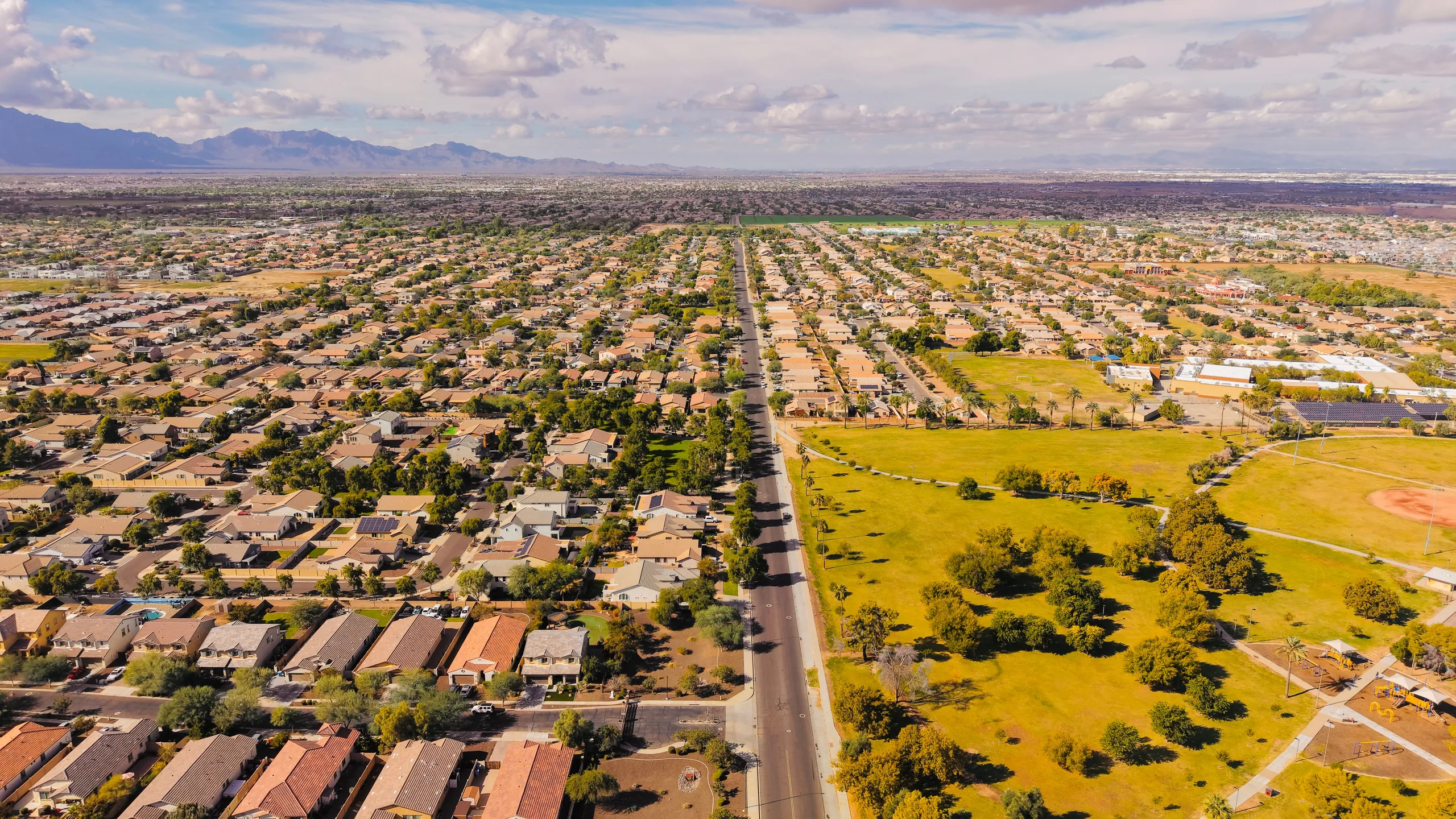 Aerial view of a sunny Arizona suburb with mountains on the horizon