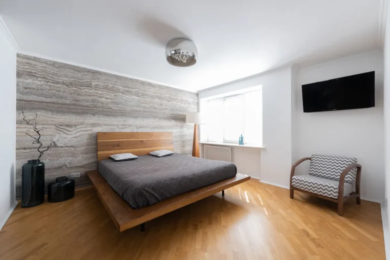 Bright bedroom with a wooden bed, an armchair and light wood floors