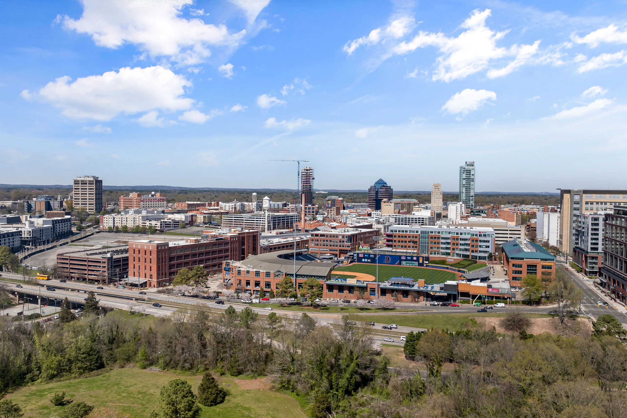 Downtown Durham skyline and baseball park beneath a blue sky