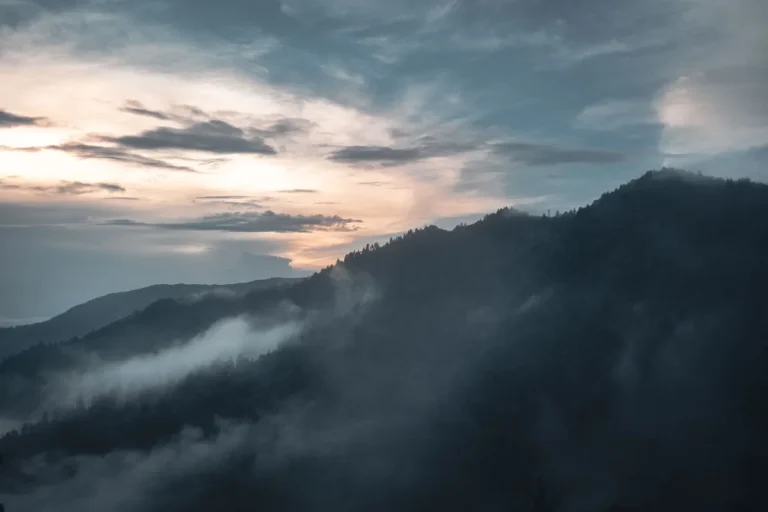 Sunrise and drifting mist over wooded mountain ridges