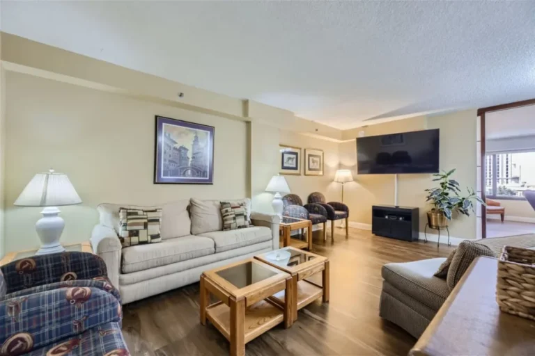 Living room with pale seating and a television in our Jockey Club condo