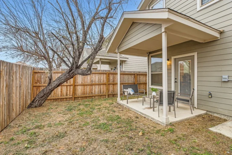 Covered backyard patio at a San Antonio rental with chairs beside a wooden fence