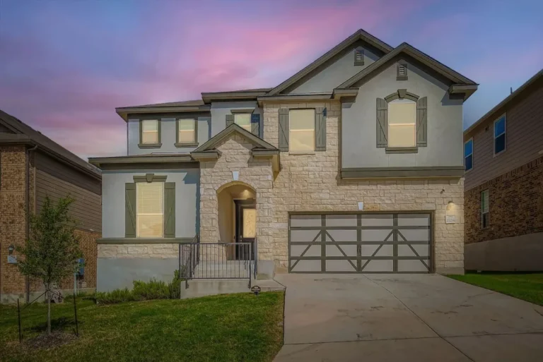 Two-story San Antonio rental with a stone entry and double garage at dusk
