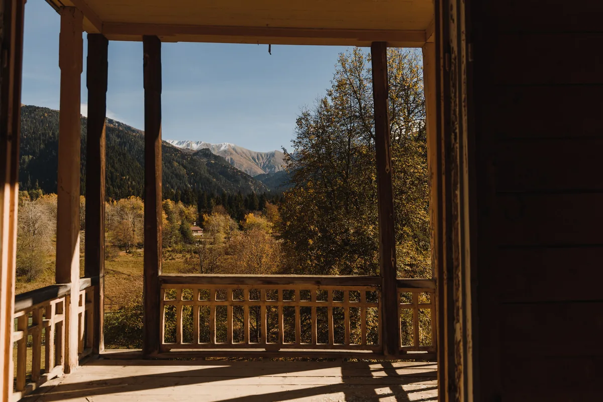 Covered wooden porch looking out at a forested mountain valley